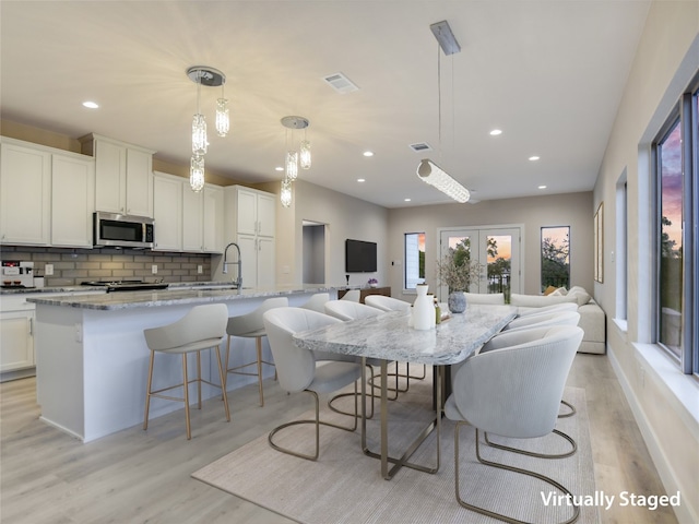 kitchen with hanging light fixtures, light hardwood / wood-style flooring, a breakfast bar area, and an island with sink