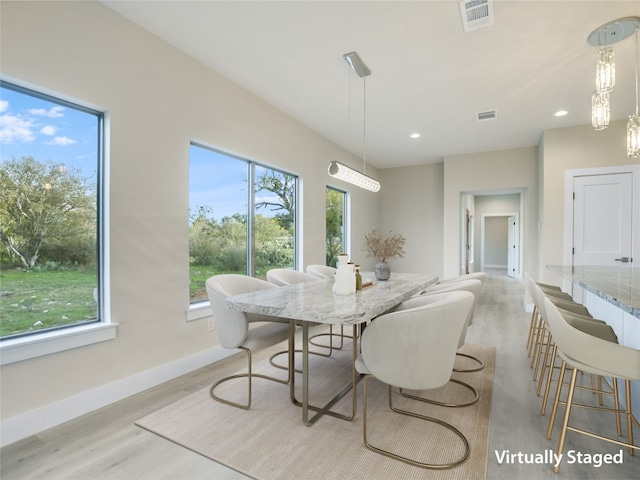 dining room with a chandelier, plenty of natural light, and light hardwood / wood-style floors