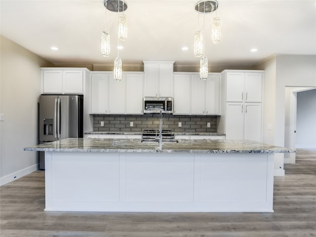 kitchen with white cabinetry, backsplash, appliances with stainless steel finishes, an island with sink, and light wood-type flooring