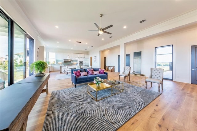 living room featuring crown molding, ceiling fan, and light hardwood / wood-style flooring