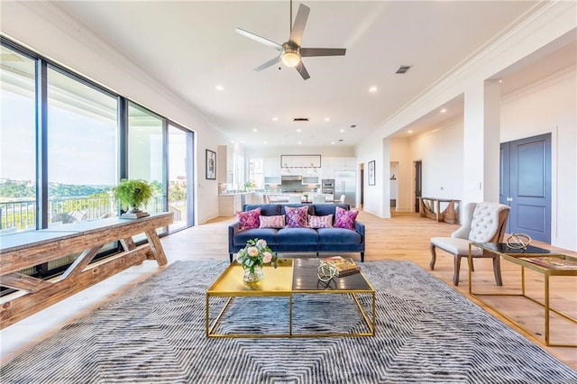 living room featuring ceiling fan, ornamental molding, and light hardwood / wood-style flooring