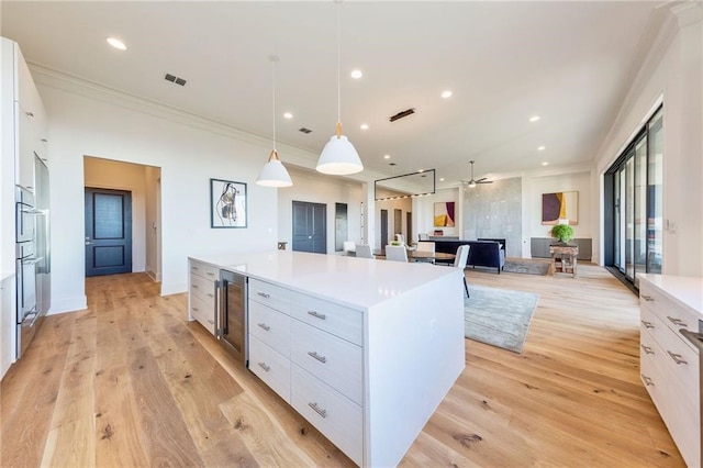 kitchen with white cabinetry, decorative light fixtures, beverage cooler, and a spacious island