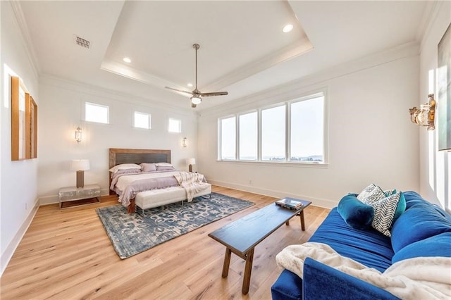 bedroom featuring a raised ceiling, crown molding, ceiling fan, and light hardwood / wood-style floors