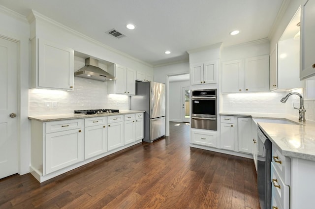 kitchen with wall chimney range hood, white cabinetry, and appliances with stainless steel finishes