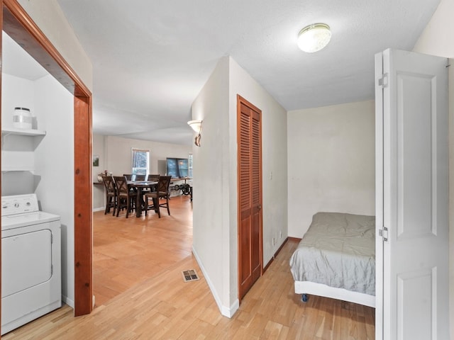 interior space featuring light wood-type flooring, a textured ceiling, and washer / dryer