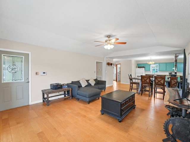 living room with a textured ceiling, light hardwood / wood-style flooring, ceiling fan, and lofted ceiling