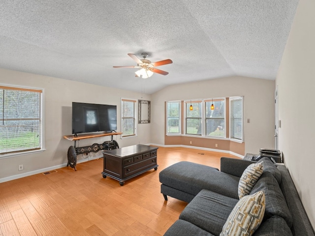 living room with plenty of natural light, ceiling fan, lofted ceiling, and light hardwood / wood-style flooring