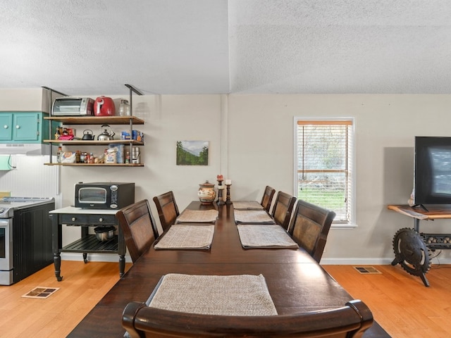 dining area with hardwood / wood-style floors, a textured ceiling, and lofted ceiling