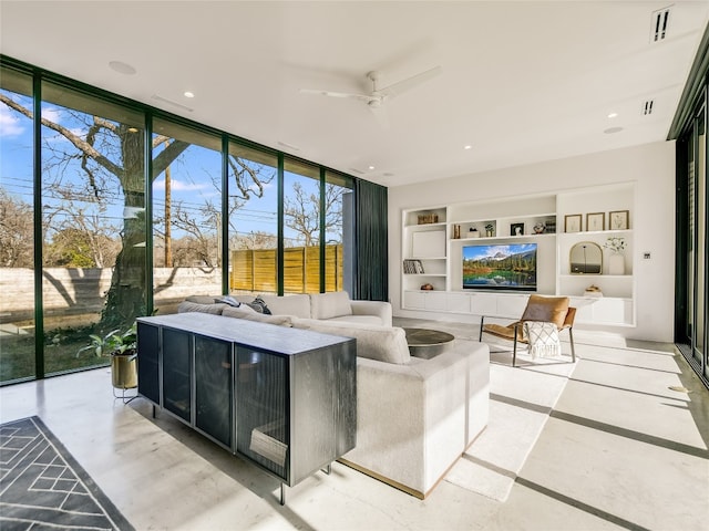 living room featuring built in features, floor to ceiling windows, ceiling fan, and a wealth of natural light