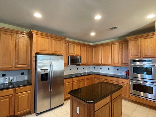 kitchen featuring dark stone countertops, a center island, light tile patterned floors, and appliances with stainless steel finishes