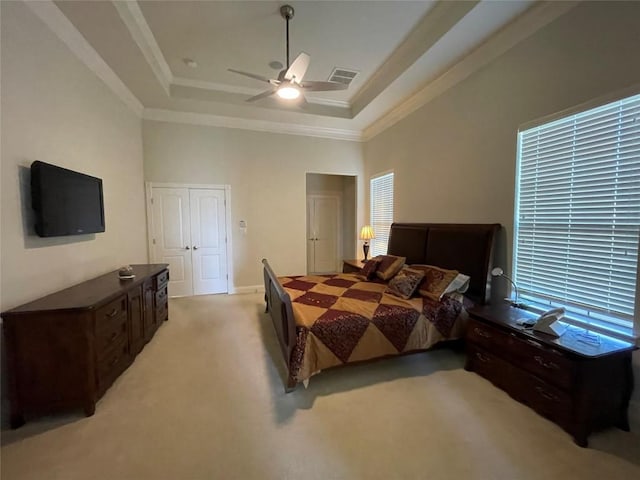 bedroom featuring light carpet, a closet, a raised ceiling, and ceiling fan