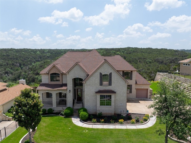 french country home featuring covered porch, a garage, and a front yard