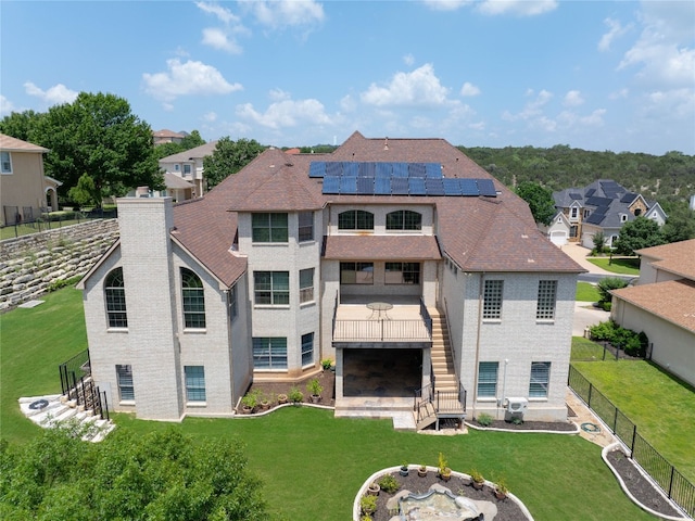 rear view of property with solar panels, a yard, and a wooden deck