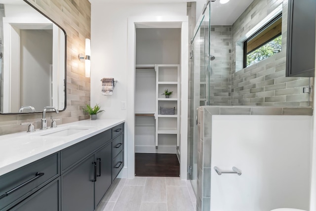 bathroom featuring tile patterned floors, vanity, backsplash, and walk in shower