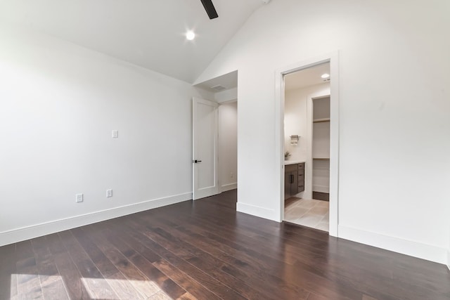 unfurnished bedroom with dark hardwood / wood-style floors, high vaulted ceiling, and ensuite bath