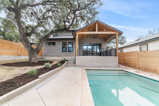 back of property featuring a fenced in pool and ceiling fan