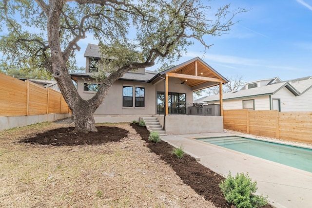 rear view of house with a sunroom, ceiling fan, and a fenced in pool