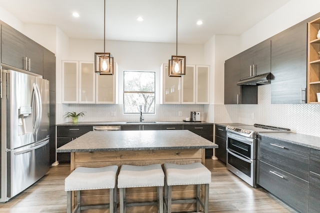 kitchen featuring a breakfast bar, appliances with stainless steel finishes, a center island, backsplash, and sink