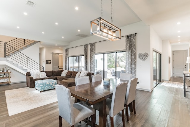 dining area with hardwood / wood-style floors, a barn door, and a chandelier