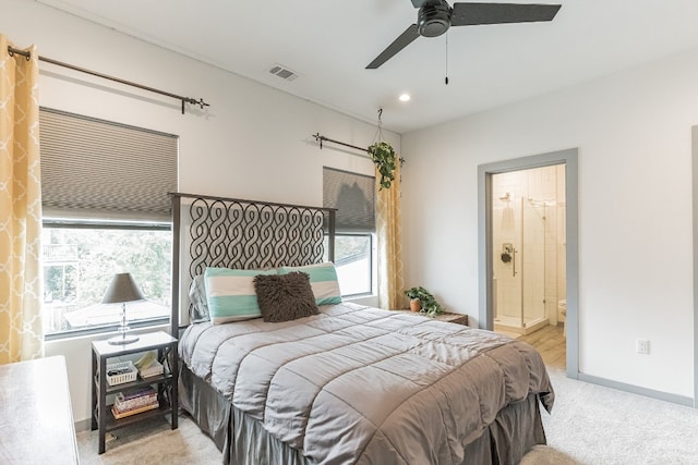 bedroom with light carpet, connected bathroom, and ceiling fan