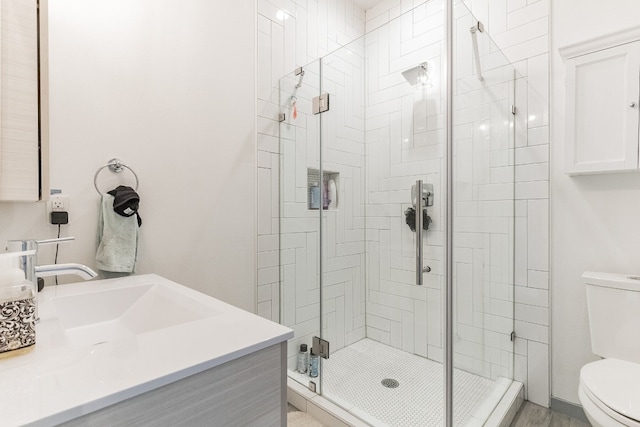 bathroom featuring vanity, a shower with door, and toilet