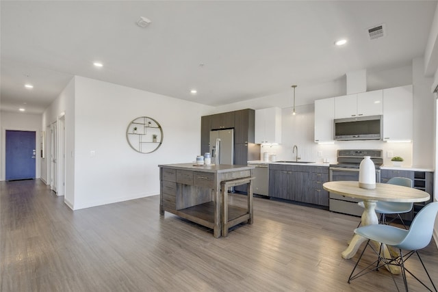 kitchen featuring light hardwood / wood-style floors, a kitchen island, backsplash, appliances with stainless steel finishes, and pendant lighting