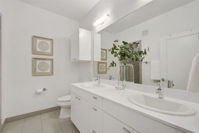 bathroom with tile flooring, vanity with extensive cabinet space, double sink, and toilet