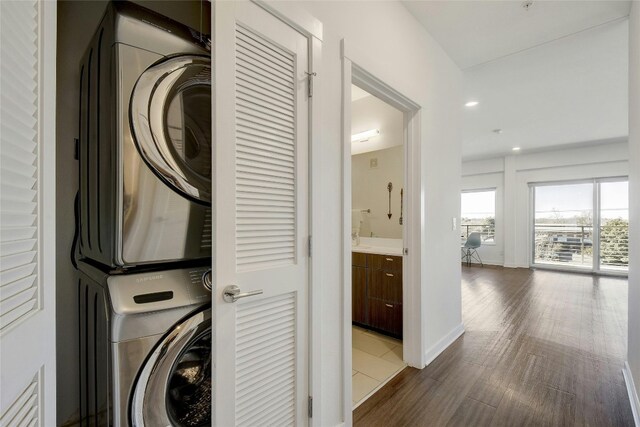 clothes washing area featuring dark hardwood / wood-style flooring and stacked washer and clothes dryer