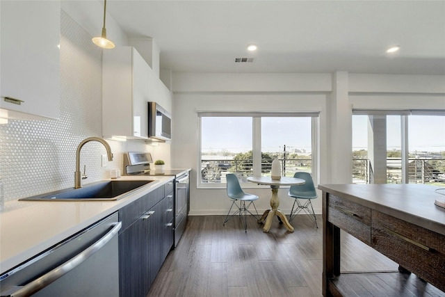 kitchen featuring hanging light fixtures, dark hardwood / wood-style flooring, appliances with stainless steel finishes, backsplash, and sink