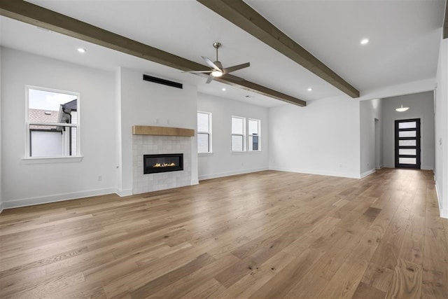 unfurnished living room featuring a fireplace, light hardwood / wood-style floors, beamed ceiling, and ceiling fan