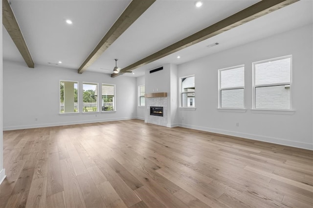 unfurnished living room featuring beamed ceiling, ceiling fan, and light hardwood / wood-style floors