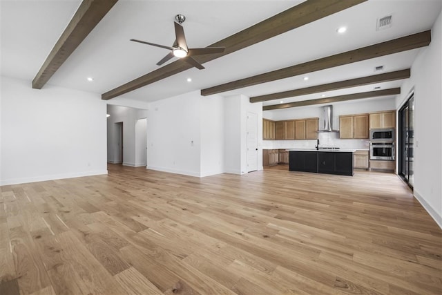 unfurnished living room featuring ceiling fan, beamed ceiling, and light hardwood / wood-style flooring