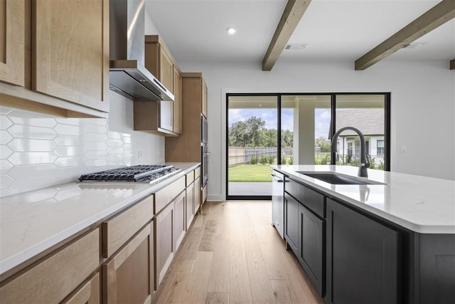 kitchen featuring stainless steel appliances, beamed ceiling, sink, wall chimney exhaust hood, and light hardwood / wood-style flooring