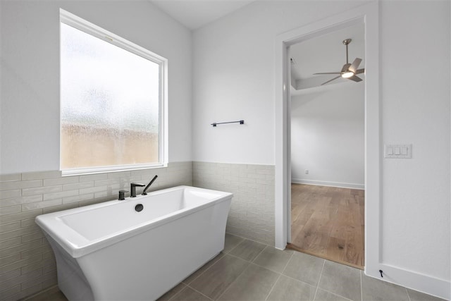 bathroom with a bathing tub, tile walls, ceiling fan, and tile patterned floors