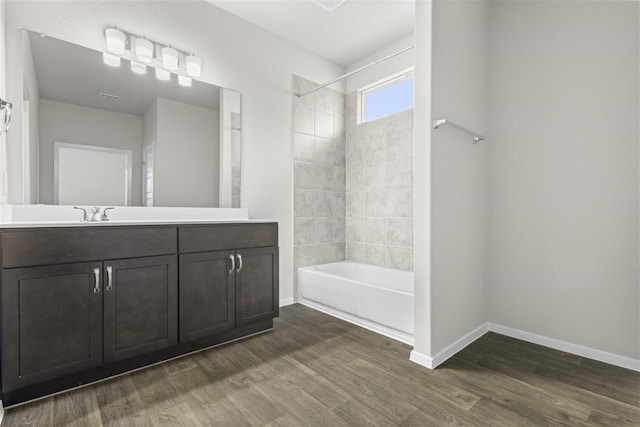 bathroom with tiled shower / bath combo, wood-type flooring, and vanity