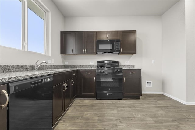 kitchen featuring light hardwood / wood-style floors, dark brown cabinets, black appliances, and sink