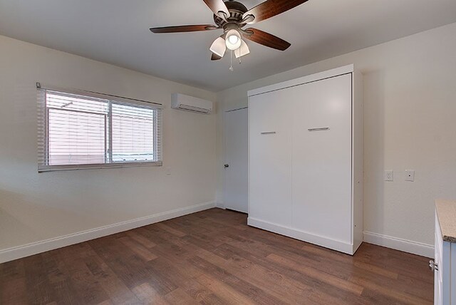 unfurnished bedroom featuring a closet, ceiling fan, dark hardwood / wood-style floors, and a wall unit AC