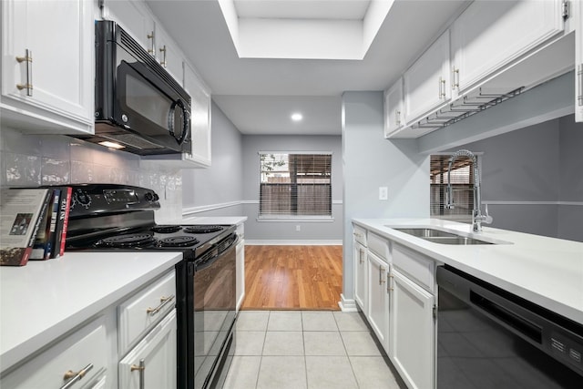 kitchen with black appliances, sink, white cabinetry, and light tile floors