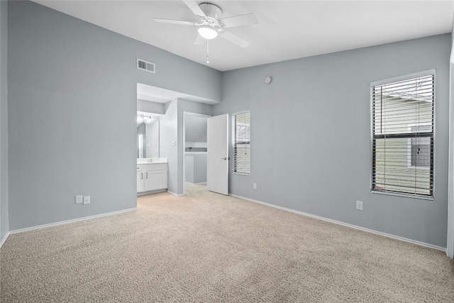 unfurnished bedroom featuring light colored carpet, ensuite bath, and ceiling fan