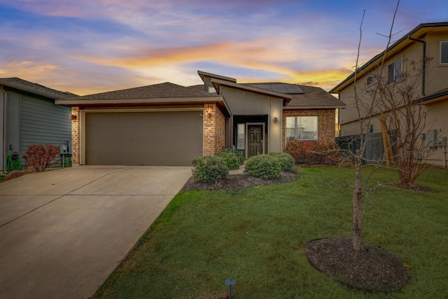 view of front of property with a garage, a lawn, and solar panels