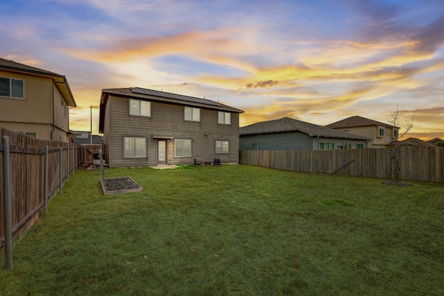 back house at dusk featuring a yard