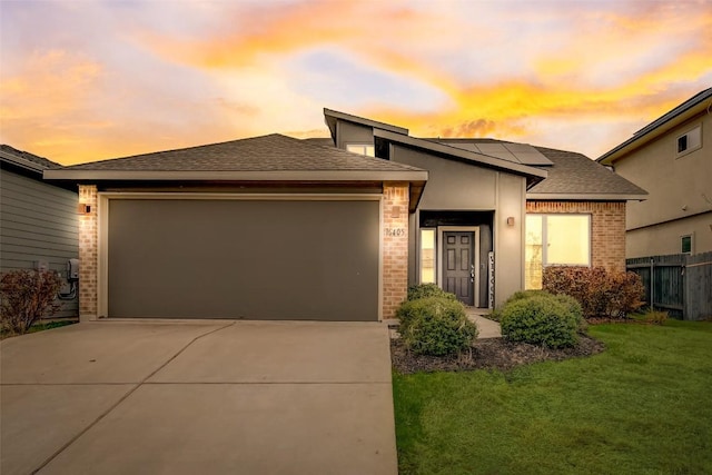 prairie-style home with a garage, a lawn, and solar panels