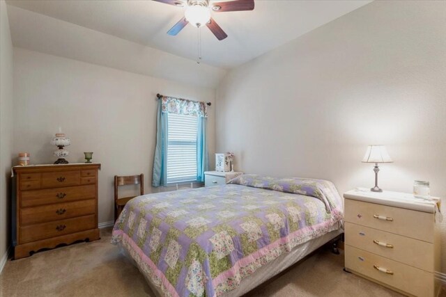 bedroom with ceiling fan, vaulted ceiling, and light carpet