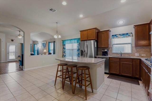 kitchen featuring sink, stainless steel appliances, decorative backsplash, and a kitchen island