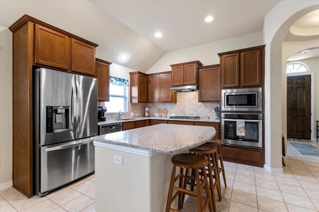 kitchen with decorative backsplash, light tile patterned floors, a center island, and stainless steel appliances