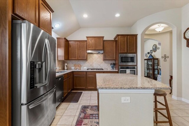 kitchen featuring tasteful backsplash, vaulted ceiling, light tile patterned floors, and stainless steel appliances