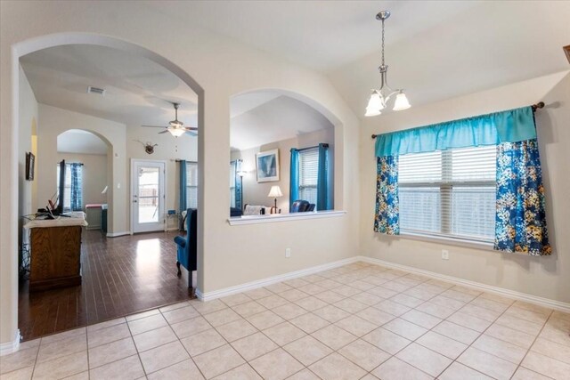 empty room featuring light tile patterned floors and ceiling fan with notable chandelier