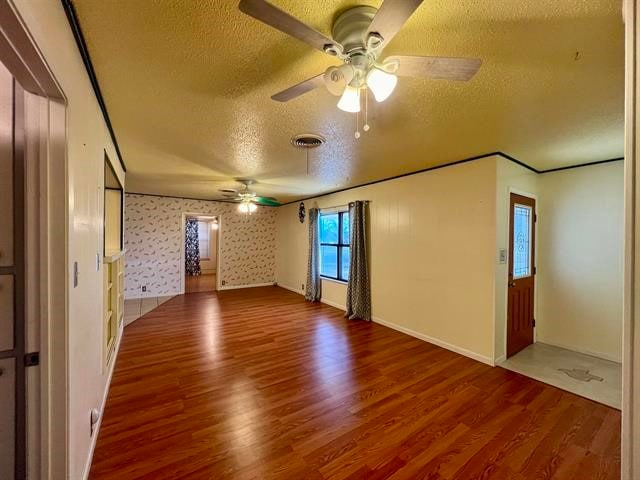 empty room with ceiling fan, a textured ceiling, and wood-type flooring