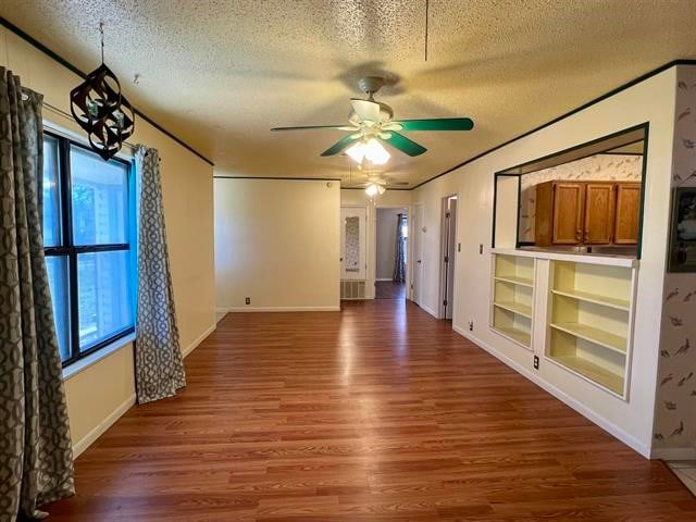 spare room with built in features, ceiling fan, a textured ceiling, and dark hardwood / wood-style floors