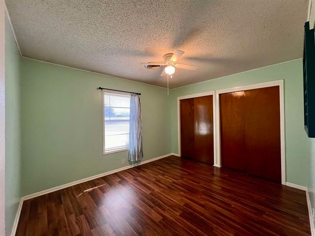 unfurnished bedroom featuring ceiling fan, a textured ceiling, and dark hardwood / wood-style flooring